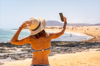 A young tourist taking a photo with the phone on the beaches of the Corralejo Natural Park