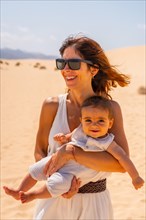 Young mother with her son very happy in the dunes of the Corralejo Natural Park