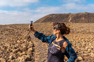 A young woman making a video next to the Crater of the Calderon Hondo volcano near Corralejo