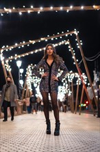 Christmas lifestyle. Caucasian brunette in a fashionable sequined dress and black shoes with heels