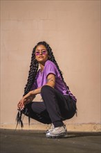 Urban session. Dark-skinned young woman with long braids and purple glasses