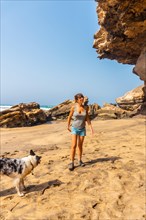 A young woman walking with the dog by the sea in Playa de Garcey