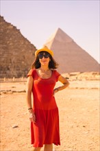 Portrait of a young girl in red dress at the pyramid of Cheops the largest pyramid. The pyramids of Giza the oldest funerary monument in the world. In the city of Cairo