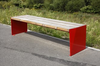 Modern red bench made of wood and metal in a park