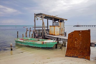 Little fishing boat on the beach and old wooden jetty on Caye Caulker