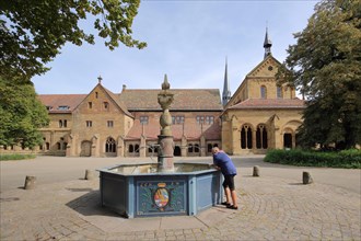 Romanesque monastery church and fountain with coat of arms of Wuerttemberg Duke Ludwig