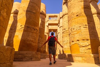 A young man walking between the columns with hieroglyphs inside the Karnak Temple