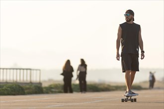 A man rides a skateboard in the early evening. Mid shot