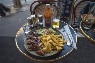 Grilled pork served with French fries in a restaurant