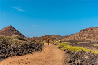 A young man with a yellow backpack on the trail heading north to Isla de Lobos