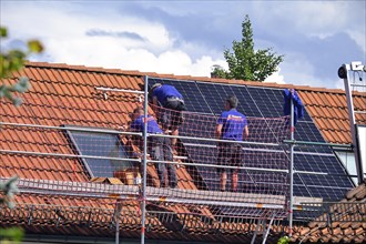 Electricians installing solar panels on a roof