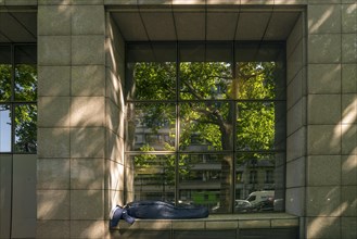 Homeless person in a window recess of an office building