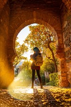 A tourist with her son at sunset at the gate of the Alcazaba wall in the city of Malaga