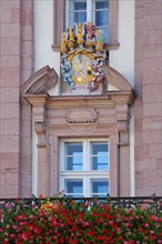 Coat of arms with lattice helmets at the window and flower decoration at the town hall