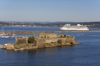 Historic fortress Castle San Anton at the harbour entrance and cruise ship Seven Seas Splendor leaving port