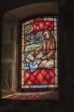 Stained-glass window showing St Samson curing man from leprosy in the Saint-Samson chapel