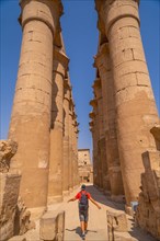 A young tourist next to the precious columns with Egyptian drawings in the Temple of Luxor