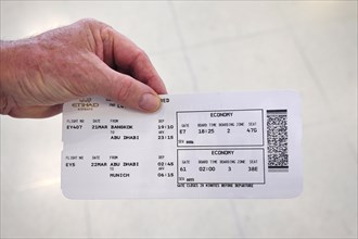 Hand holding Etihad Airways boarding pass