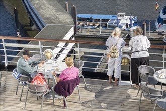 Passengers sitting at a table on the Lido Deck of the cruise ship Vasco da Gama moored at the Ueberseebruecke in the Port of Hamburg