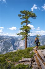 A young man with a brown jacket in Sentinel Dome looking at Upper Yosemite Fall