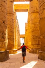 A young man strolling between the hieroglyphic columns of the Temple of Karnak