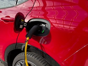 Red eco-friendly e-car electric powered car vehicle brand Alfa Romeo is charged with e-plug type 2 plug type 2 plug Mennekes standard for Europe