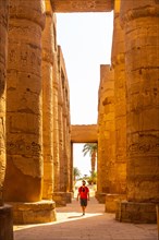 A young man strolling between the hieroglyphic columns of the Temple of Karnak