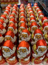 Display in shelf of wholesale of chocolate Father Christmases Nikolaus Nikolaeuse colour red of red staniol paper of chocolate in brand Lindt arranged like army of Father Christmas