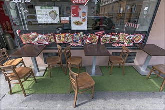 Seating and promotional photos of vegan and vegetarian dishes in front of a restaurant