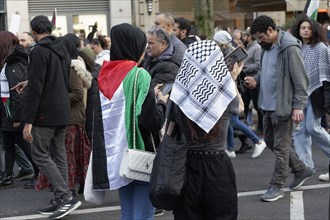 Demo participants with Palestine flag and Palestinian scarf
