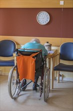 Old woman sitting bent over in a wheelchair