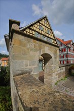 Historic town wall with archway and half-timbered house