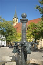 Ox fountain by Gunther Stilling with sculptures bull heads and cross church
