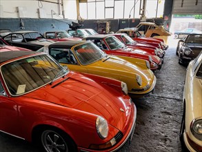 Several classic cars Porsche 911 from the 60s are standing in large hall waiting for preparation
