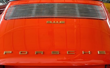 Rear of classic car Porsche 911 E from the 60s in orange colour with typical radiator grille