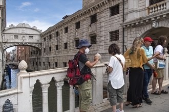 Tourists on the Ponte de Paglia visit the Bridge of Sighs