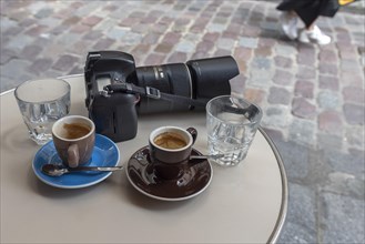 Two espressos and camera on a bistro table of a cafe