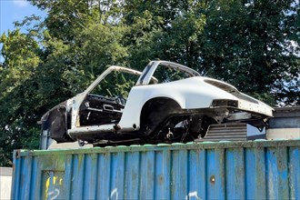 Old body of Porsche 911 Targa in colour white stands on container outside waiting for restoration