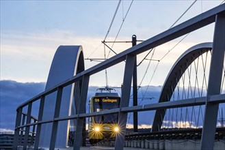 Network arch bridge over the A8 motorway. Light rail bridge of the SSB for the U6 airport line. The span of the arches is 80 metres. Tension elements made of carbon. The U6 line light rail bridge rece...