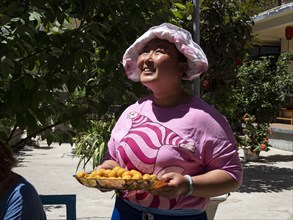 Chinese woman with hat brings apricots