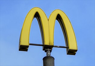 Giant pole-mounted logo yellow M of fast food restaurant McDonald's