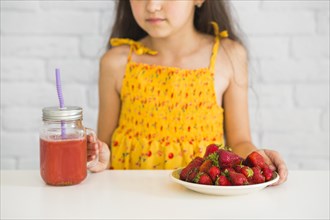 Close up girl holding plate strawberries smoothies jar