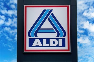 Logo and lettering Aldi in blue with red frame in front of supermarket of retail chain supermarket chain Aldi Nord