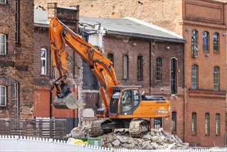 Demolition excavator in front of historic brick buildings