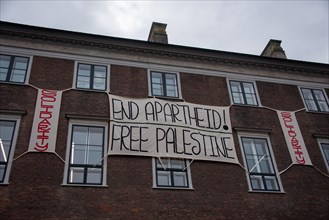 A banner with the words End Apartheid! hangs on a building. Free Palestine