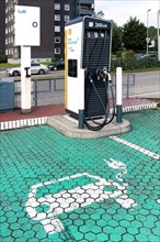Charging station from Shell with 300 kw power for e-cars in front of it green paved parking bay marked with symbol for electric car