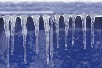 Close-up of icicles against a blue plastic background