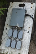 Locked grey metal electrical distribution box and outlets for plugging in extension cords