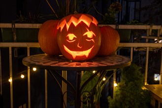 Carved pumpkin stands on a balcony on Halloween evening