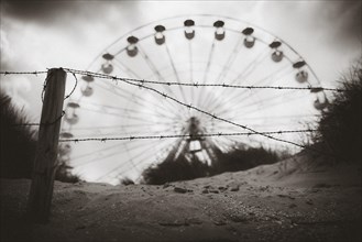 Ferris wheel behind barbed wire on the beach of De Panne